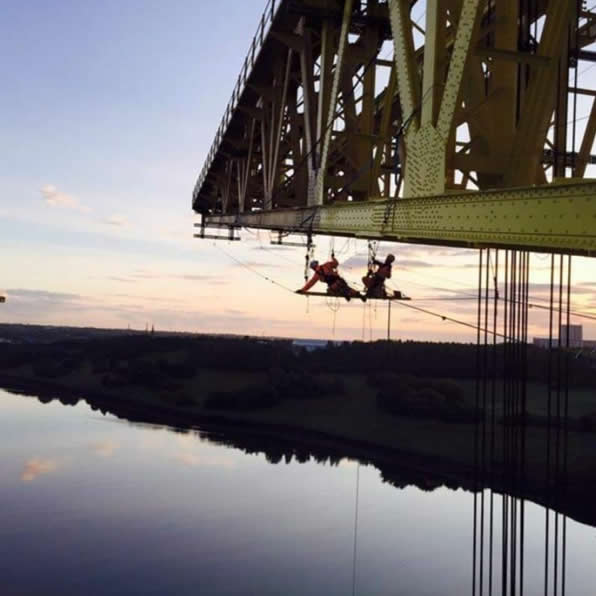 Technician working beneath a large steel bridge structure