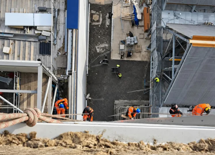 Rope access technicians working on an industrial building, viewed from above